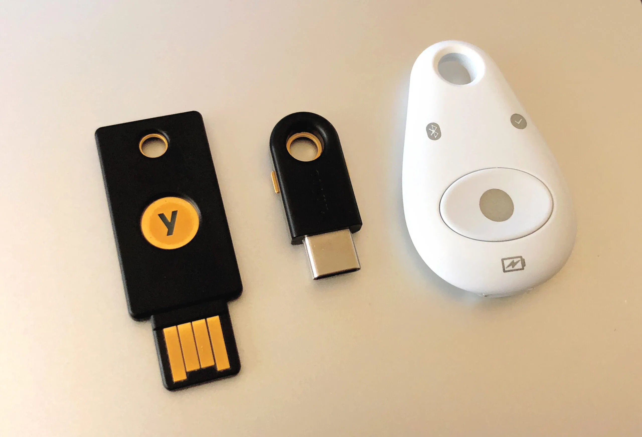 Drie verschillende beveiligingstokens liggen op een lichte ondergrond: twee zijn USB-apparaten en één is een draadloze token