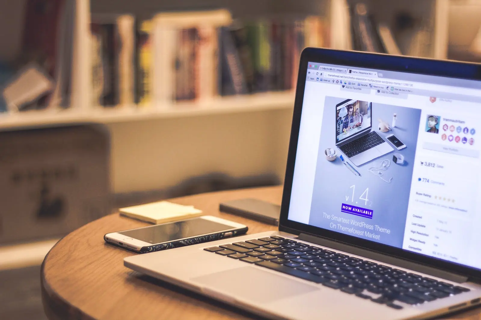 Een open laptop met een WordPress thema advertentie op het scherm, naast een smartphone en notitieblok op een houten tafe
