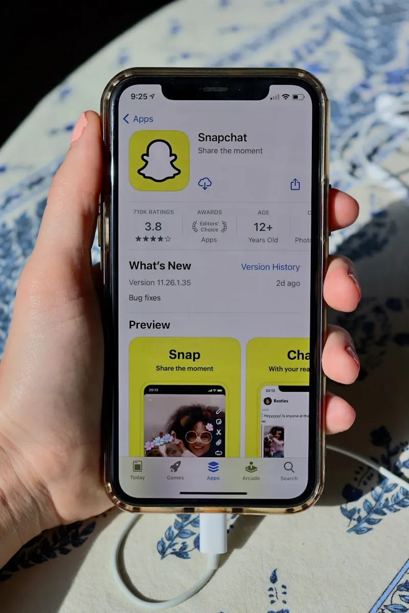 Een persoon houdt een smartphone vast met het Snapchat-app downloadscherm open in de app store
