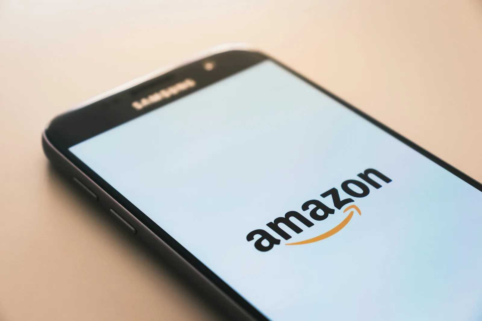 Een Samsung-smartphone op een lichtgekleurde ondergrond met het Amazon-logo op het scherm