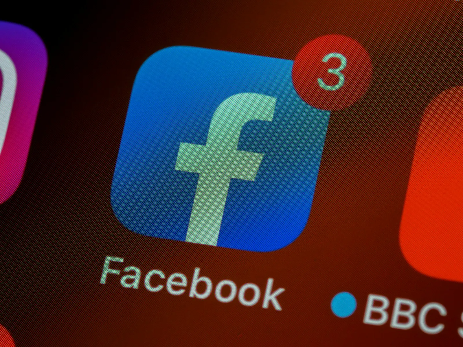 Close-up van het Facebook-app icoon met een notificatiebadge die '3' aangeeft op een smartphone scherm